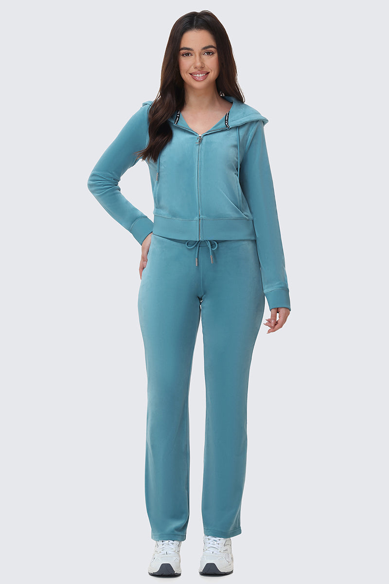 A woman wearing a Y2K teal velour zip-up hoodie and matching OG Big Bling Velour Track Pants with a drawstring waist.