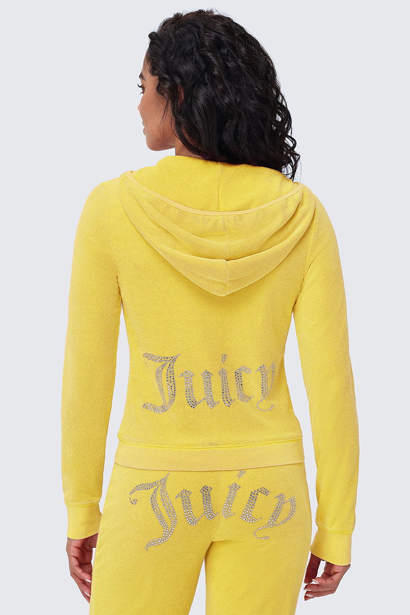 A person with curly hair faces away, wearing a yellow Big Bling Washed Terry Hoodie velour tracksuit adorned with rhinestone Juicy logos on the back of both the hoodie and pants.