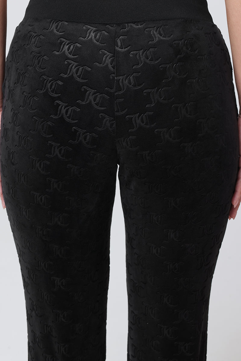 Embossed Velour Track Pants in black plush velour featuring an all-over embossed logo pattern and a wide elastic waistband.