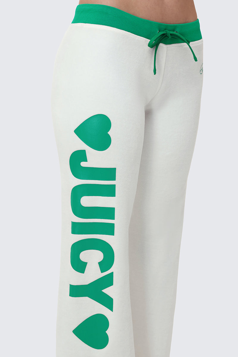 The Contrast Low Rise Track Pants are white with a green waistband and drawstring, featuring "JUICY" in bold green letters with heart accents, vertically printed on the left leg. Enjoy a relaxed fit and sporty style for all-day comfort.