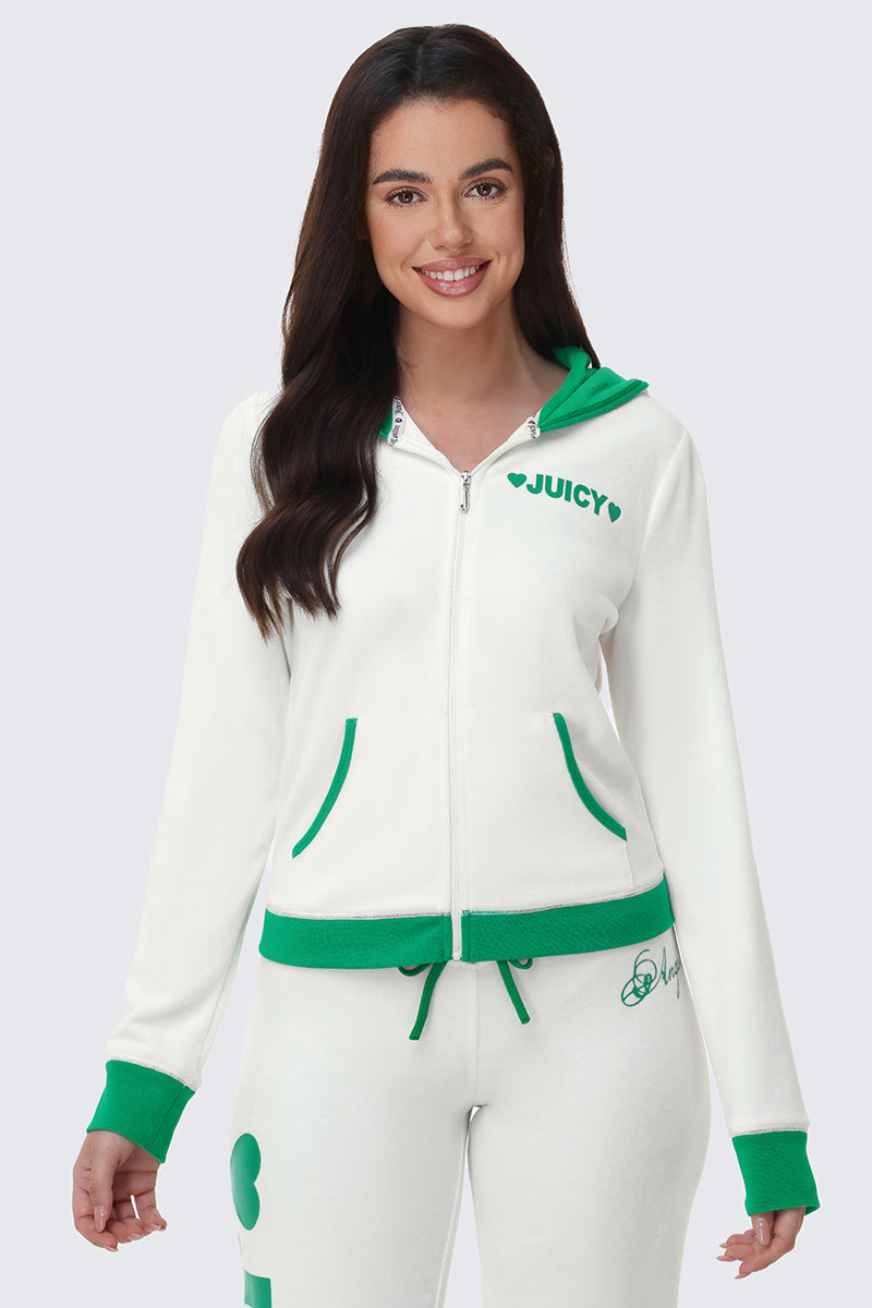 A woman with long dark hair smiles while wearing the Contrast Trim Logo Hoodie in white with green accents and "JUICY" on the chest, paired with matching white and green sweatpants. She stands against a plain light background.