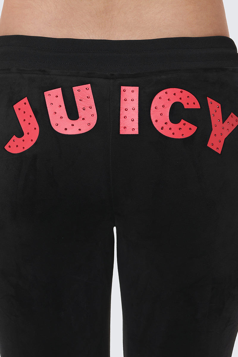Close-up of the Cherry Bling Velour Jogger's back, showing "JUICY" in bold, red studded letters across the waistband and a comfy drawstring waist.