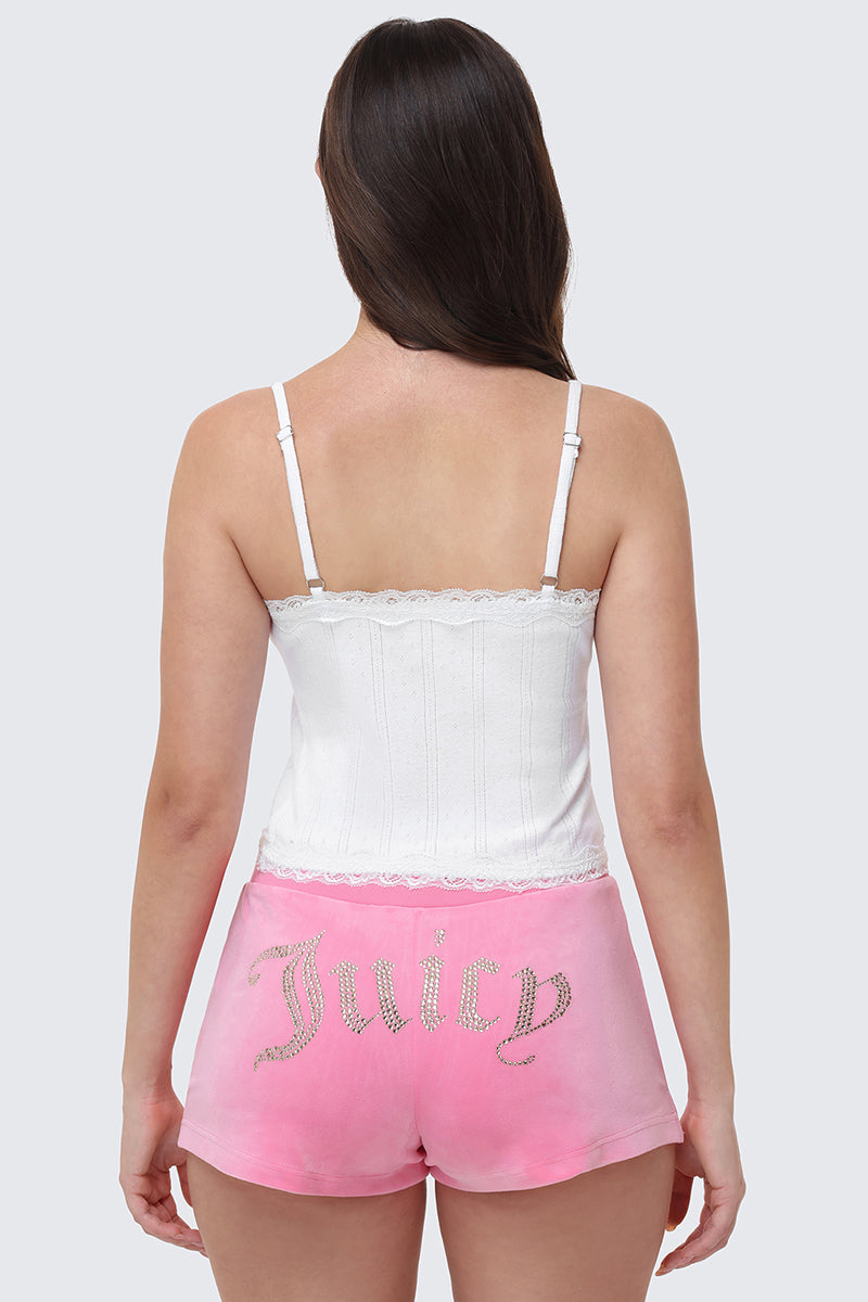 A woman is shown from the back, wearing a white Bling Lace Trim Cami with lace details, paired with pink shorts featuring a rhinestone Juicy logo on the back.