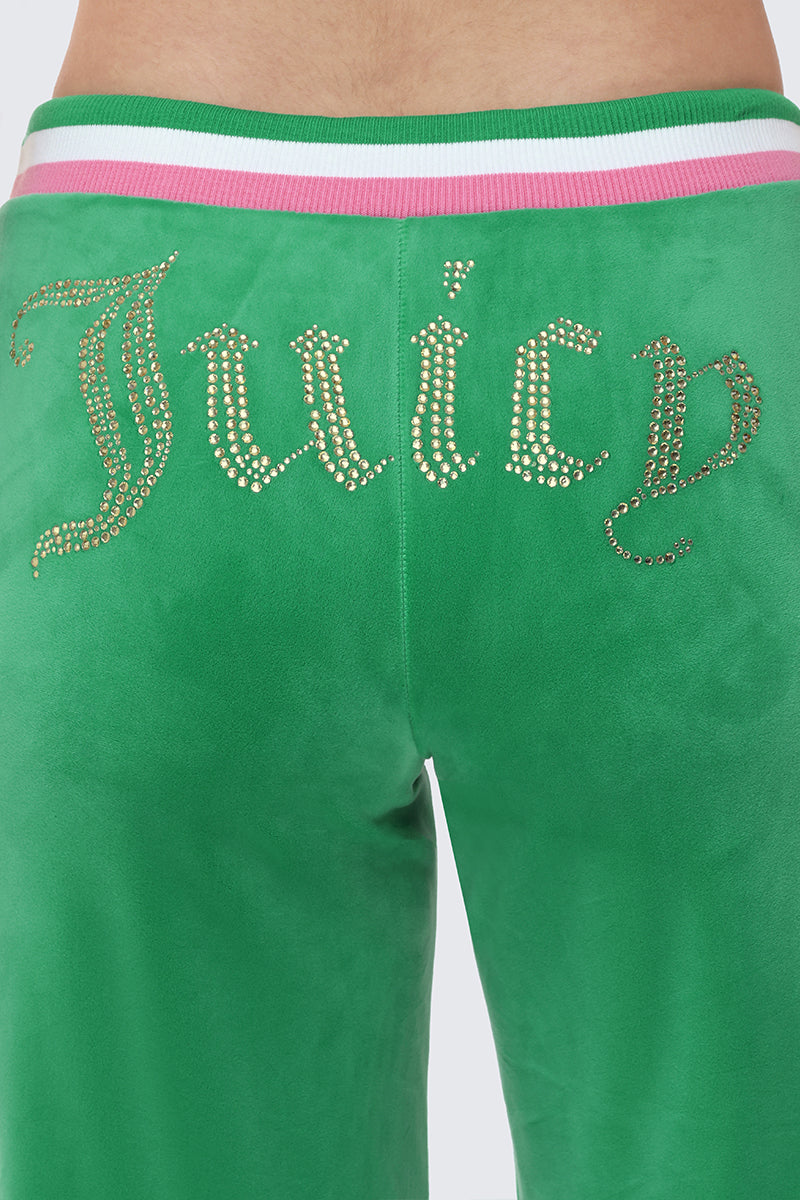 Close-up of the back of a person wearing Heritage Stripe Bling Velour Track Pants in bright green, showcasing a rhinestone Juicy logo below a pink and white striped waistband.