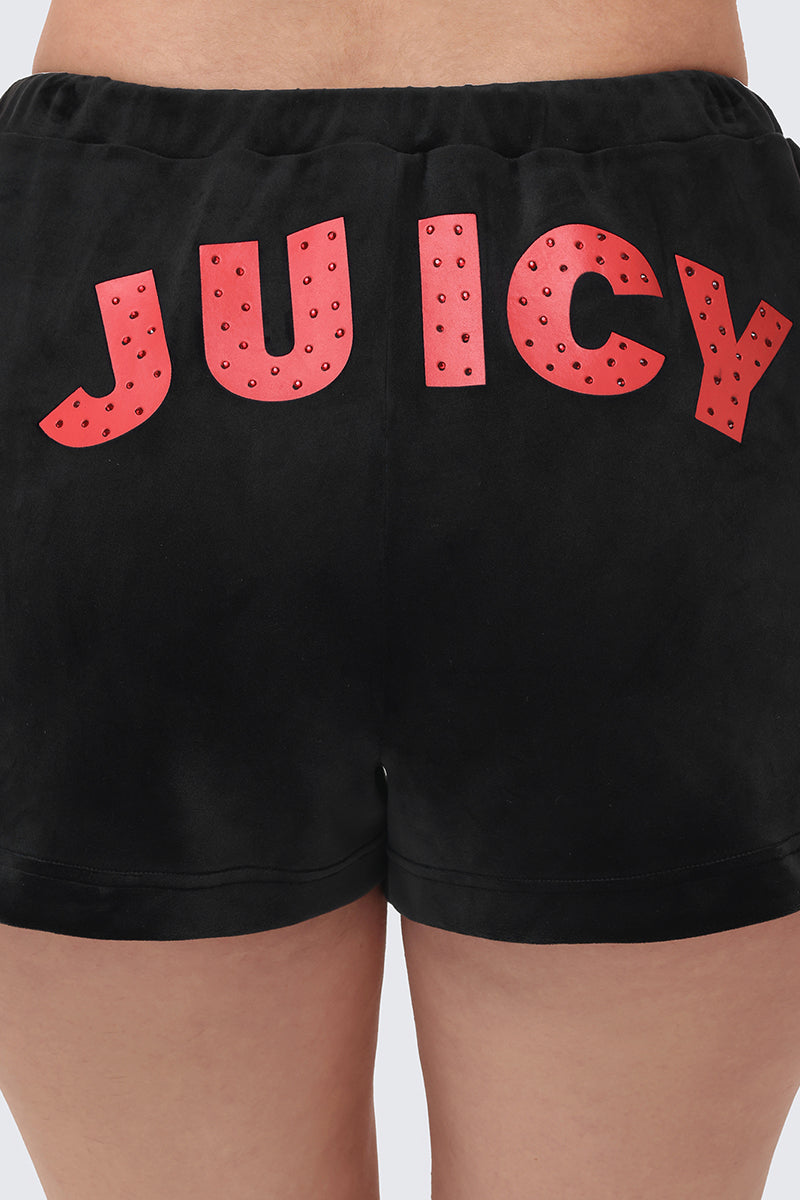 A person wearing Cherry Bling Velour Shorts with "JUICY" in large red letters and small studs on the back.