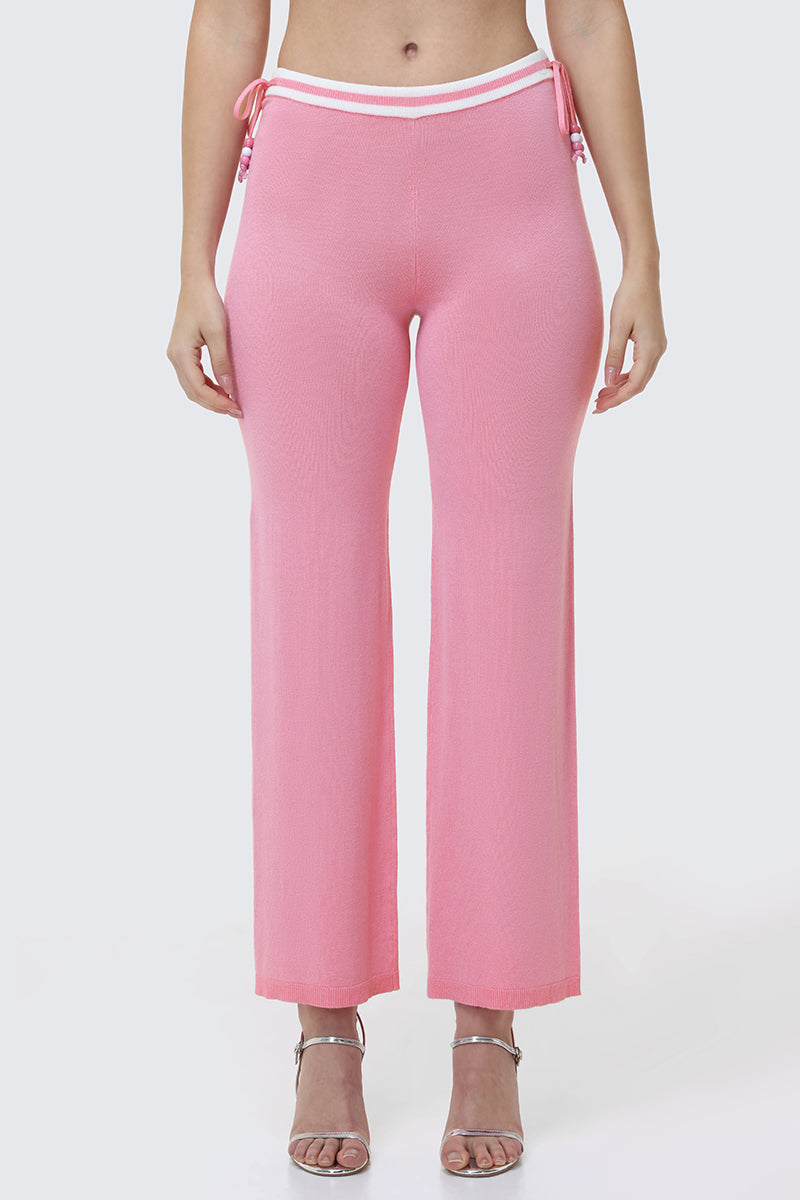 Someone wears the Big Bling Wide Leg Pants—high-waisted, pink, with a ribbed texture, contrast striped waistband, and side ties—paired with silver heeled sandals against a plain light background.