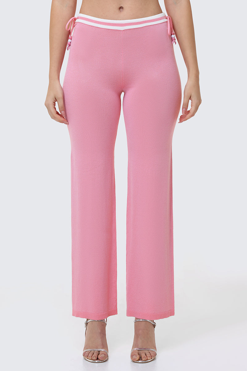 Wearing the Big Bling Wide Leg Pants—high-waisted, light pink, ribbed with a contrast striped waistband and side ties—paired with open-toe heels, against a plain light background.
