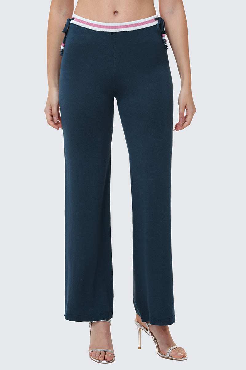 A woman models the Big Bling Wide Leg Pants in dark blue with ribbed fabric, a contrast striped waistband, and side ties, styled with strappy high-heeled sandals. The image captures her from shoulders to feet against a plain background.