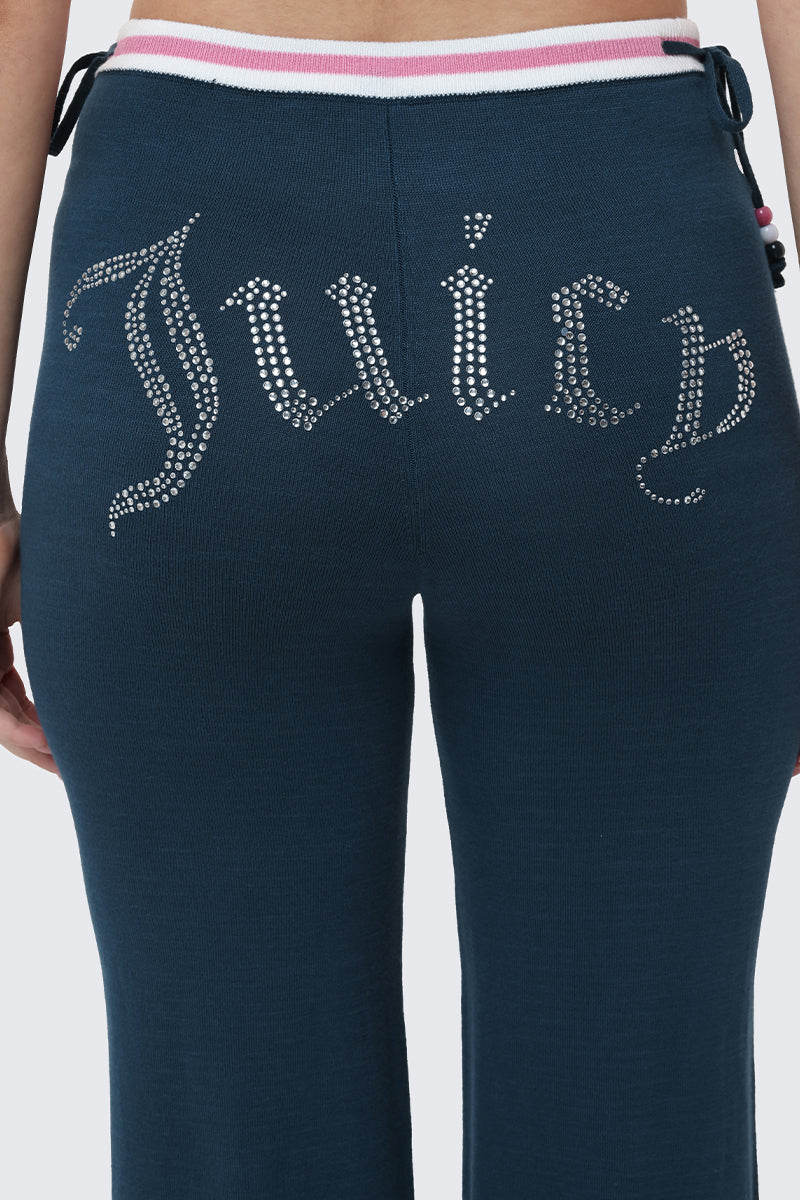 A close-up of a person wearing the Big Bling Wide Leg Pants, featuring a rhinestone Juicy logo across the back and a bold, contrast striped waistband with eye-catching white and pink stripes.