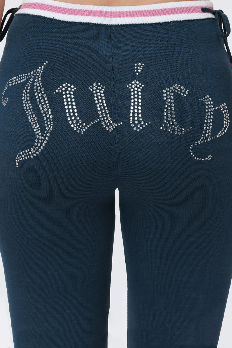 Close-up of the back of the Big Bling Wide Leg Pants in dark blue velour with ribbing, showing the Juicy logo in silver rhinestones below a contrast striped waistband.