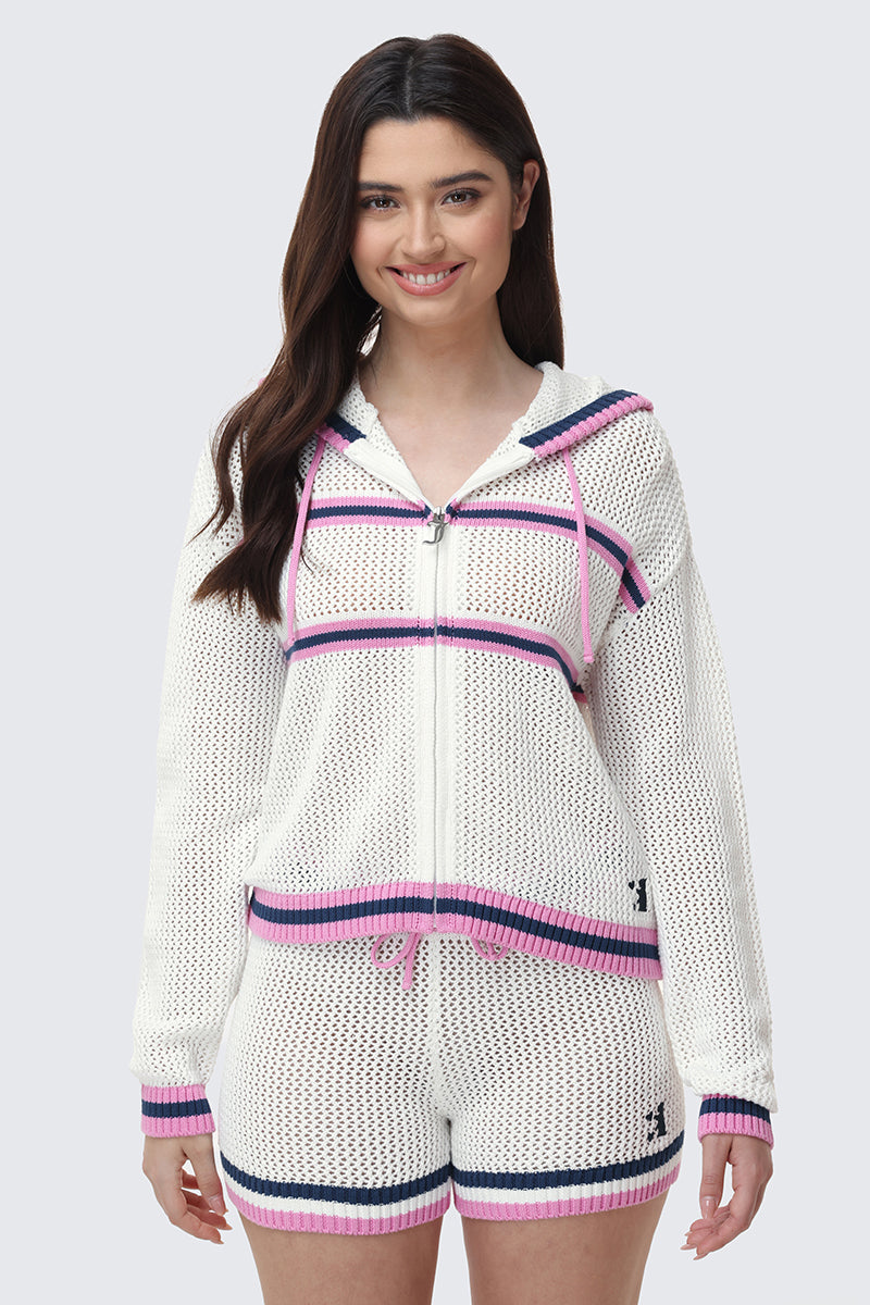 A woman with long brown hair smiles while wearing the Mesh Zip-Up Hoodie and matching shorts with pink, navy, and purple stripes. She stands against a plain light grey background.