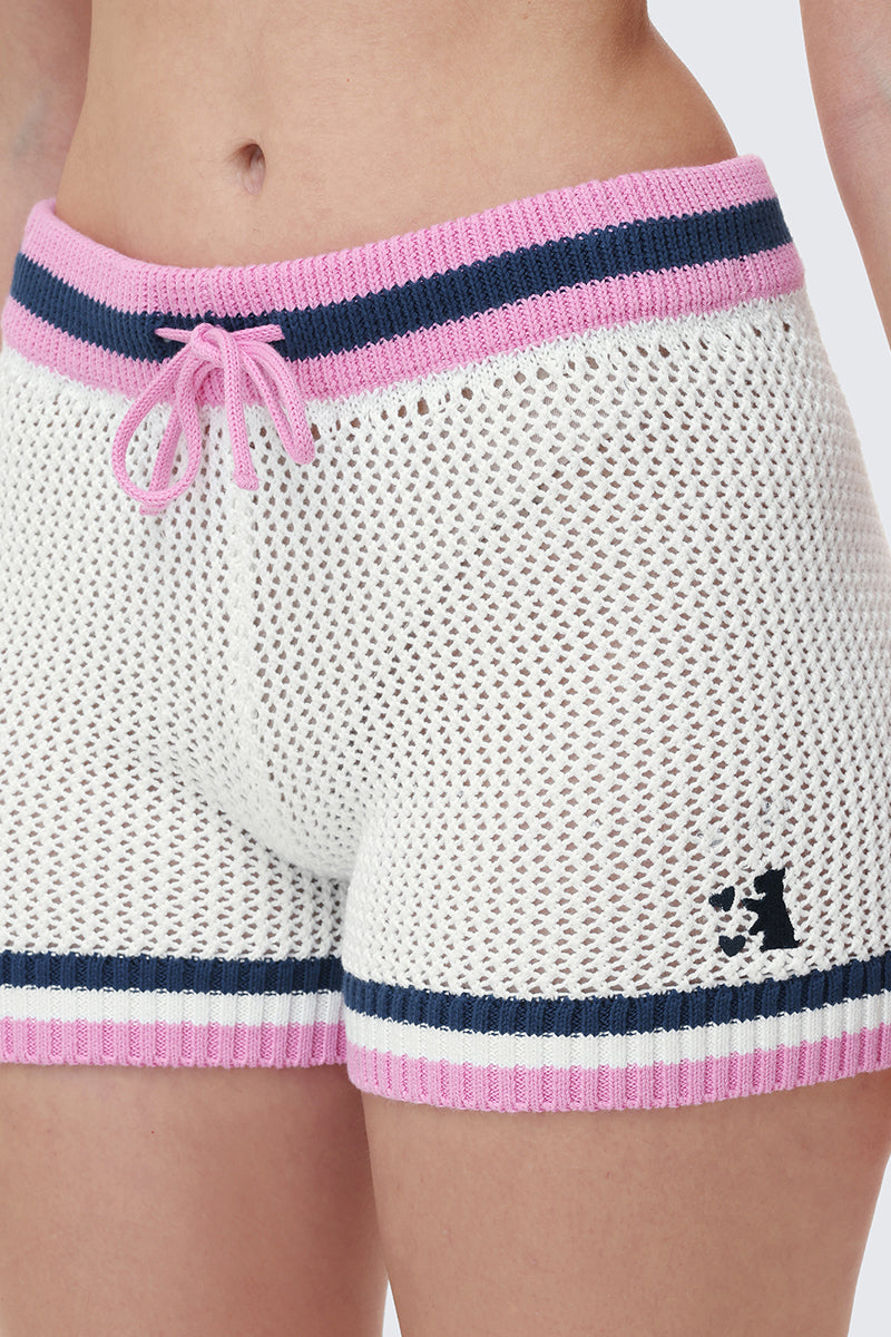 Someone in Mesh Shorts featuring white crochet knit mesh, pink and navy blue stripes at the waistband and leg openings, and a pink drawstring at the waist for a sporty-chic vibe.