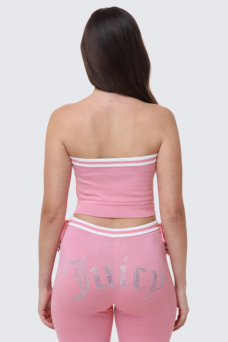 A woman faces away from the camera, wearing the Big Bling Tube Top in pink and matching pink pants with "Juicy" in silver rhinestones across the back.