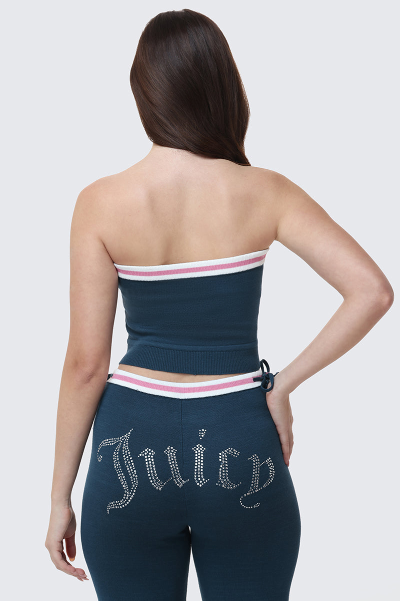 A woman is seen from behind wearing the Big Bling Tube Top, a strapless blue top with white and pink stripes, paired with matching blue pants featuring "Juicy" in rhinestones on the back.