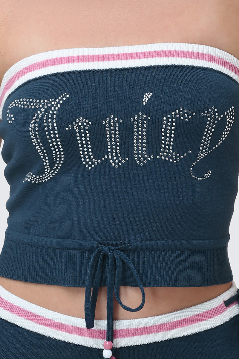 A close-up of a person wearing the Big Bling Tube Top—a blue strapless top with “Juicy” in silver rhinestones, white and pink trim, a drawstring waist, and matching bottoms partially visible.