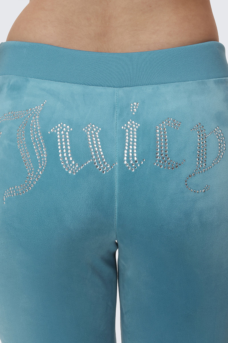 Close-up of the back of a person wearing OG Big Bling Velour Track Pants in light blue, featuring Y2K-inspired style and "Juicy" spelled out in rhinestones across the seat.
