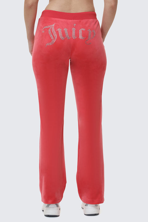 A person stands in iconic Y2K style, wearing OG Big Bling Velour Track Pants in bright pink with rhinestones across the back and white sneakers, shown from behind.