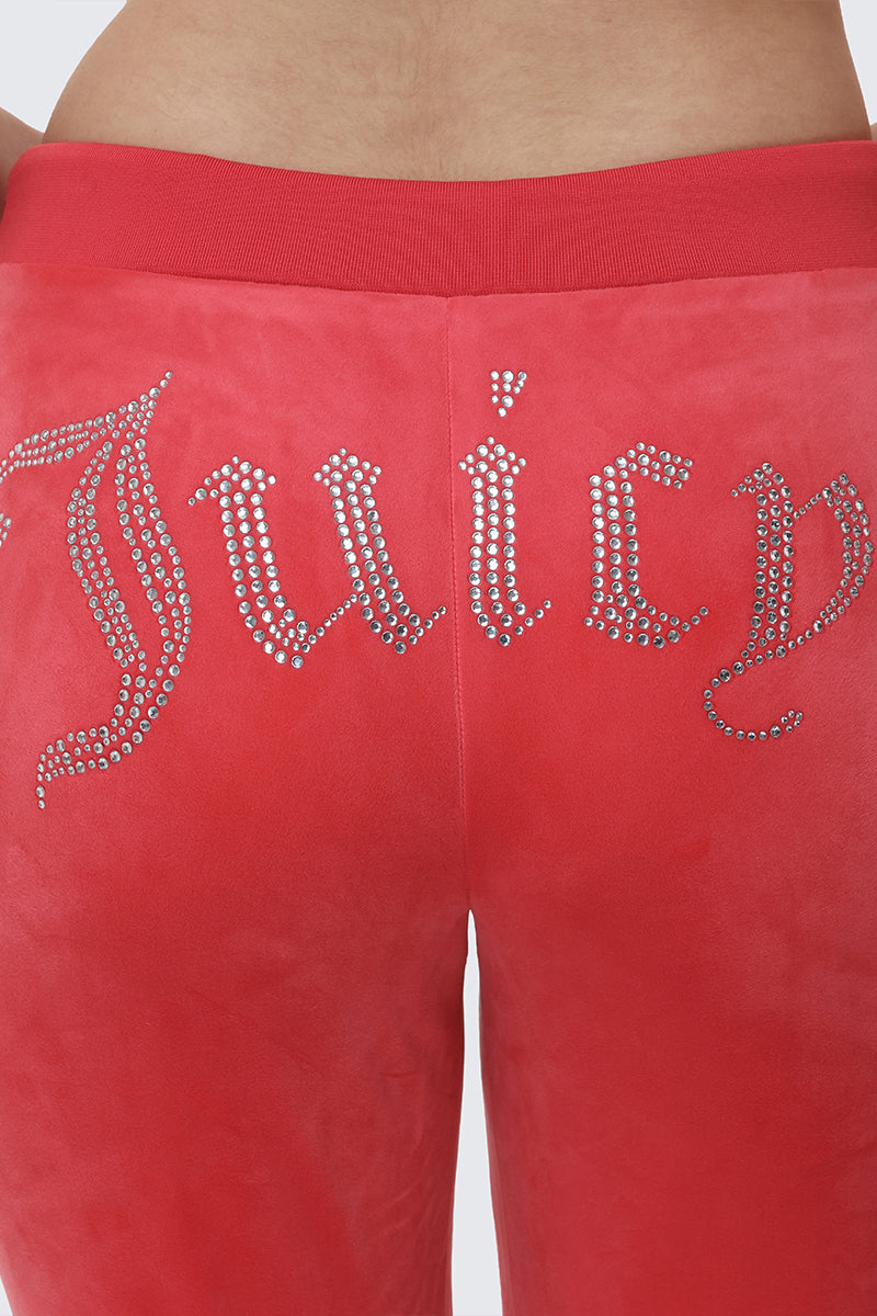 A close-up of a person in OG Big Bling Velour Track Pants, featuring "Juicy" spelled out in rhinestones across the back.
