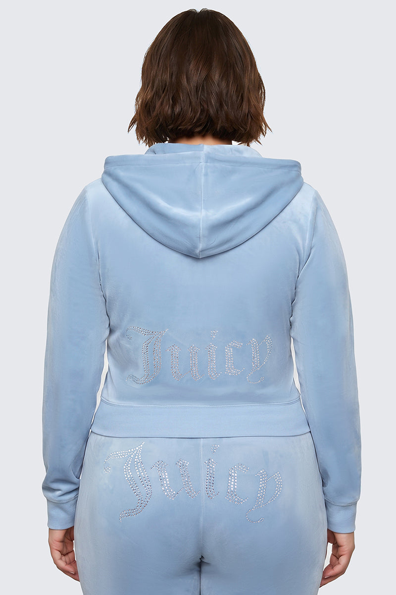A person wearing the Plus-Size OG Big Bling Velour Hoodie in light blue, featuring the iconic Juicy logo in rhinestones on the back of the jacket, channeling ultimate Y2K vibes.