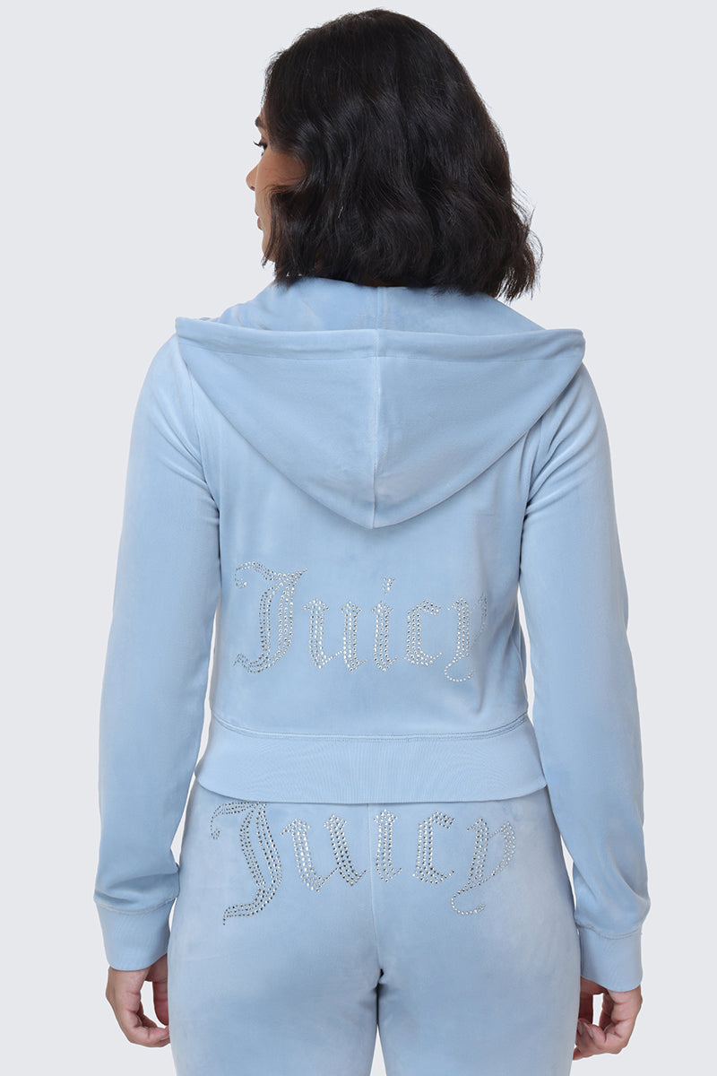 A person wearing the OG Big Bling Velour Hoodie in light blue, featuring a rhinestone Juicy logo sparkling across the back. Facing away from the camera, they show off this iconic Y2K Juicy Couture look from behind.