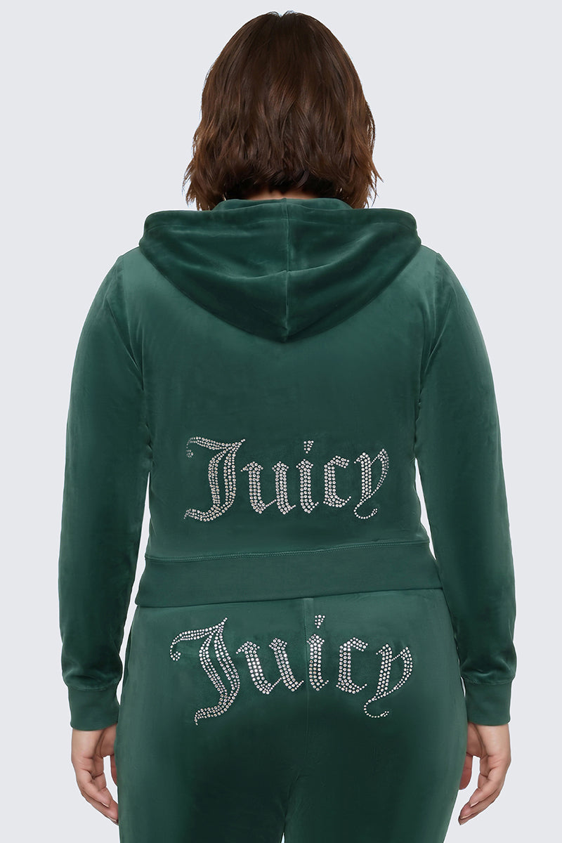 A person is seen from behind wearing the Plus-Size OG Big Bling Velour Hoodie in green. The bedazzled hoodie showcases the iconic rhinestone Juicy logo in shimmering letters across the back and on the seat of the pants, capturing a classic Y2K vibe.