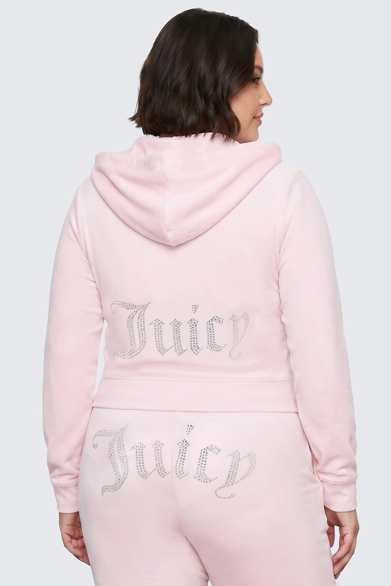 Wearing the Plus-Size OG Big Bling Velour Hoodie in light pink, featuring a sparkling rhinestone Juicy logo on the back, a person channels true Y2K vibes as they stand against a plain light background, facing away from the camera.