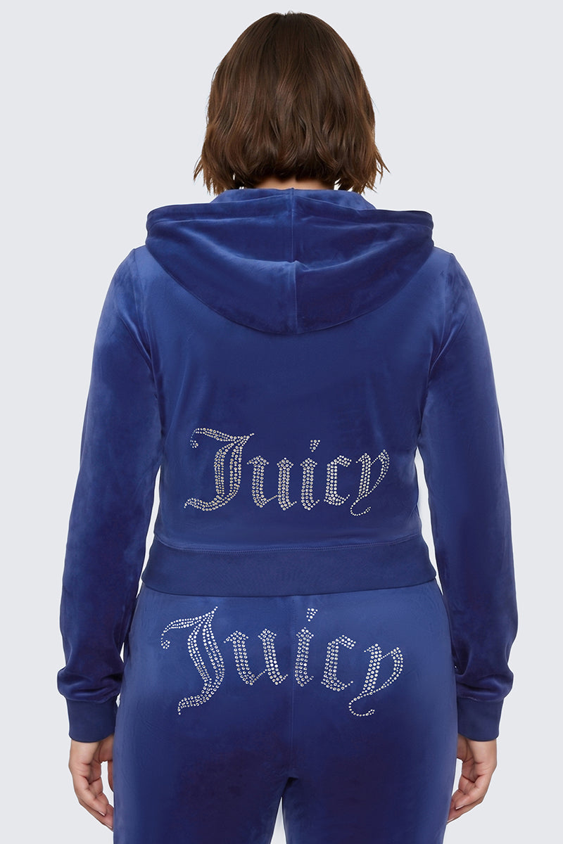 A person is seen from behind wearing the Plus-Size OG Big Bling Velour Hoodie in blue, featuring a sparkling rhinestone Juicy logo across the back, channeling classic Y2K style.