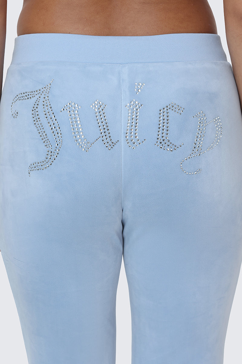 Wearing the OG Big Bling Velour Track Pants in light blue, featuring a Y2K-inspired design with a sparkling Juicy rhinestone embellishment across the back.
