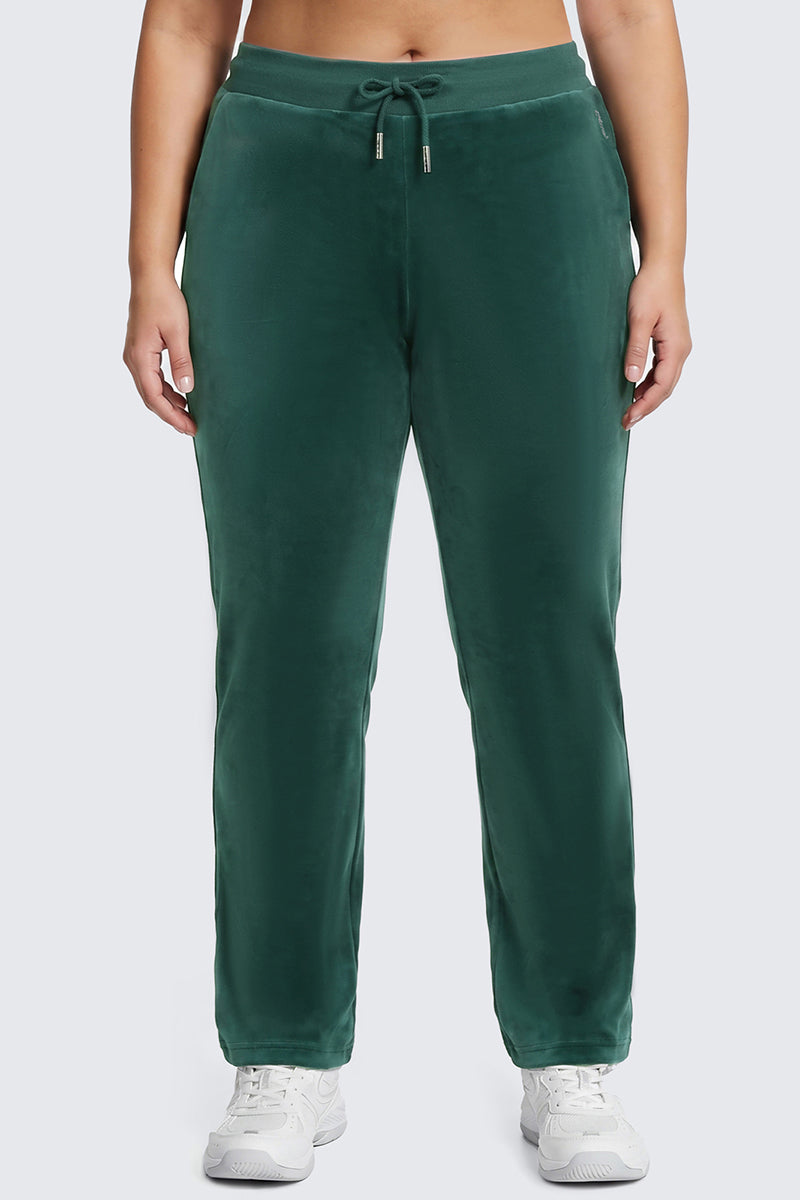 A person wearing the Plus-Size OG Big Bling Velour Track Pants in forest green, styled with a drawstring and paired with white sneakers, standing against a light gray background.