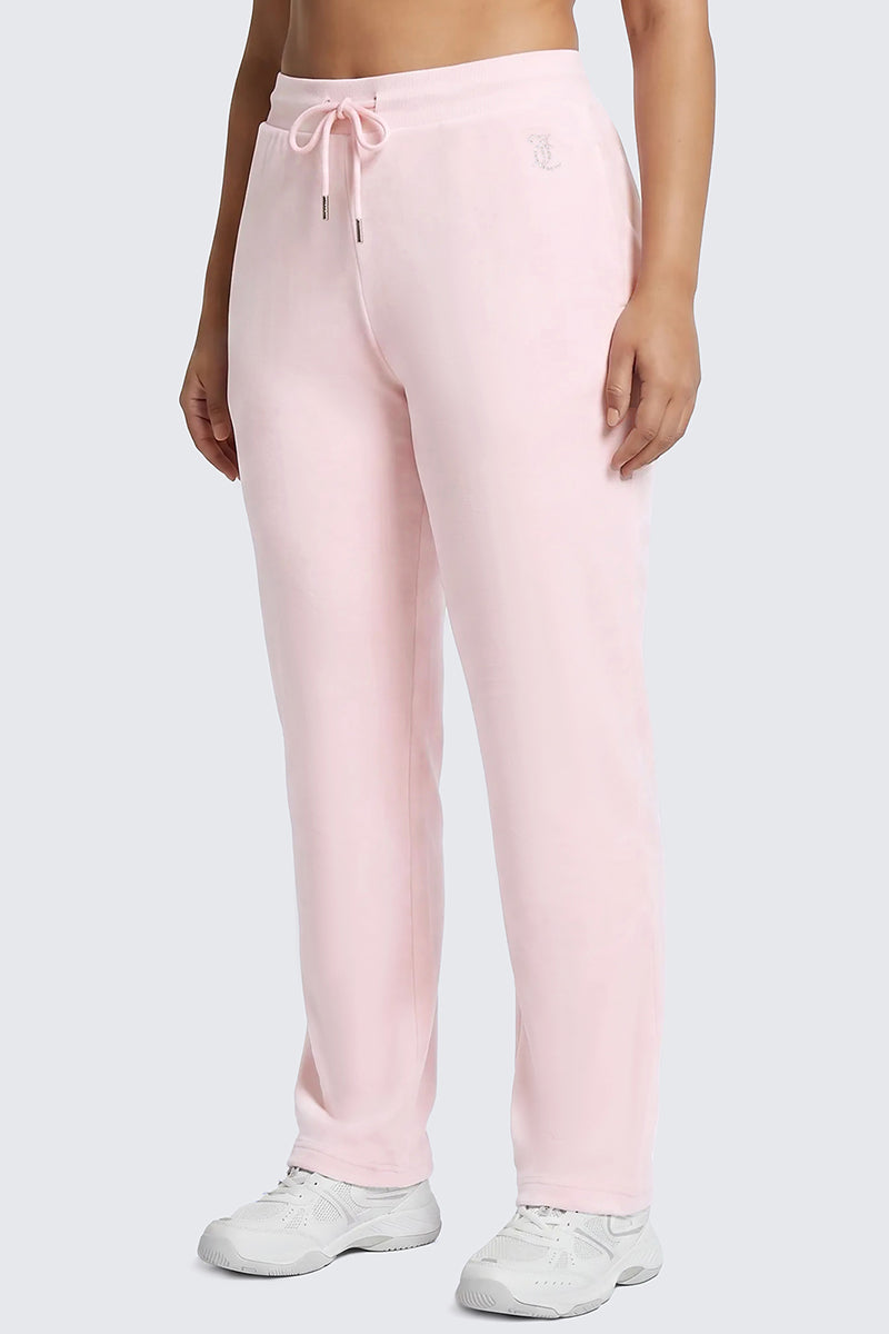 A person is wearing the Plus-Size OG Big Bling Velour Track Pants in a light pink, Y2K-inspired style with a relaxed drawstring fit and white sneakers, standing against a plain gray background. Their hands are at their sides and their face is not visible.