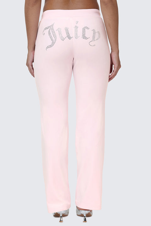 Wearing the OG Big Bling Velour Track Pants in light pink, featuring a sparkling rhinestone Juicy embellishment across the back, this look channels classic Y2K style against a plain gray background.