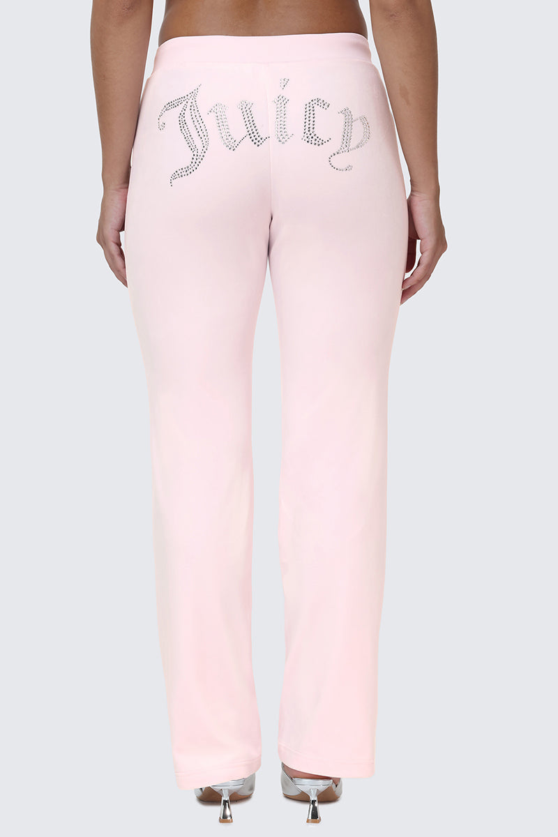 Wearing the OG Big Bling Velour Track Pants in light pink, featuring a sparkling rhinestone Juicy embellishment across the back, this look channels classic Y2K style against a plain gray background.