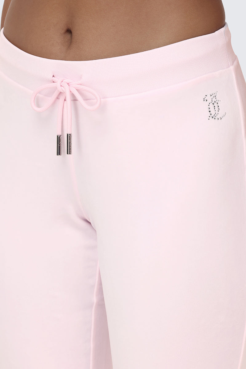Close-up of a person wearing the OG Big Bling Velour Track Pants in light pink, featuring a tied drawstring and sparkling rhinestone initials near the waistband for signature Juicy embellishment and a fun Y2K flair.