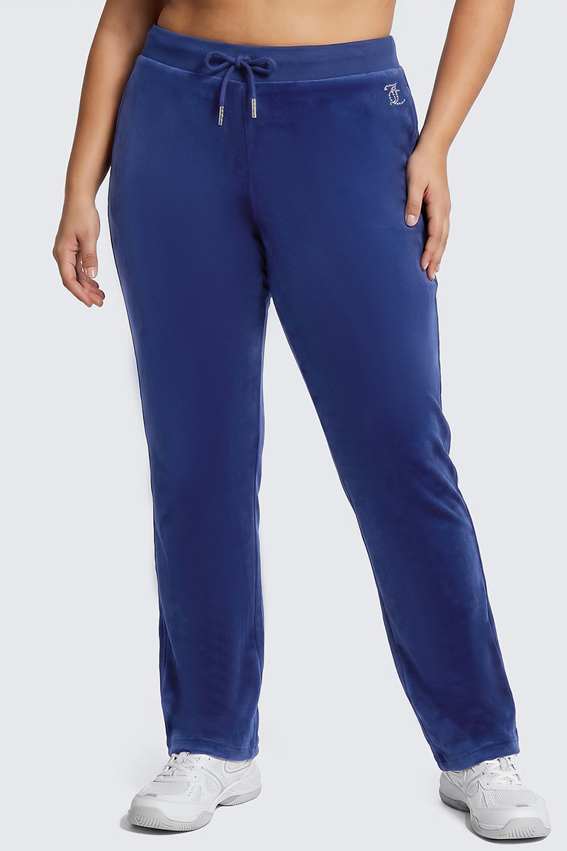Model wears the Plus-Size OG Big Bling Velour Track Pants in blue, featuring a drawstring waist, styled with white sneakers and set against a plain light gray background for an effortlessly cool Y2K vibe.