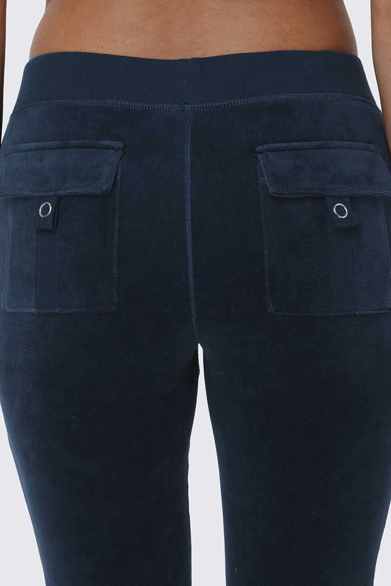 Close-up of a person wearing the Scottie Cotton Velour Track Pants in dark blue, channeling true Y2K style with snap back pockets and two flap pockets featuring silver button details for an iconic Juicy-inspired look.