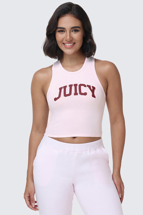 A woman with shoulder-length dark hair wears the Collegiate Juicy High Neck Tank Top in light pink, featuring a bold red JUICY logo in a collegiate style. She pairs it with matching light pink pants, standing against a plain light gray background and smiling.
