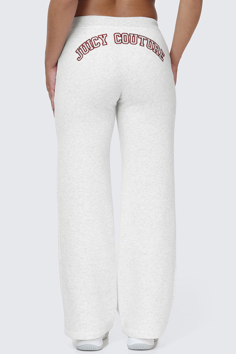 Wearing the Small Bling Fleece Wide Leg Pants, which feature a white fleece fabric, rhinestone Juicy logo detail, and a drawstring waistband, the person stands with their back to the camera against a plain, light background.