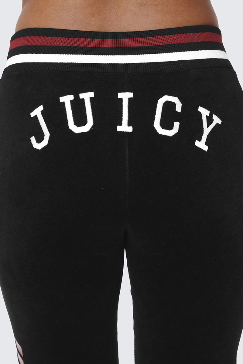 A close-up of the back of the Mixed Logo Cotton Velour Jogger shows black velour fabric with bold white block letters spelling JUICY across the waistband. Red and white stripes accent this sporty staple just above the striking logo.
