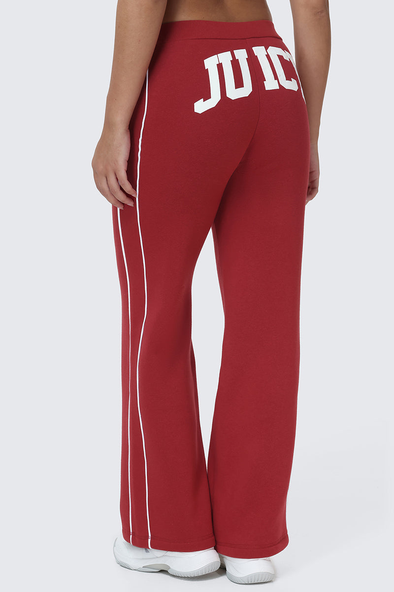 A person shown from behind wearing Scottie Fleece Wide Leg Pants in red, featuring white stripes and the bold Juicy logo in large white letters across the back.