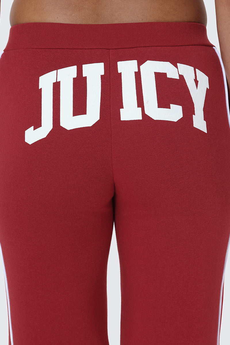 Close-up of a person wearing Scottie Fleece Wide Leg Pants in red, featuring the word "JUICY" in bold white letters printed across the back.