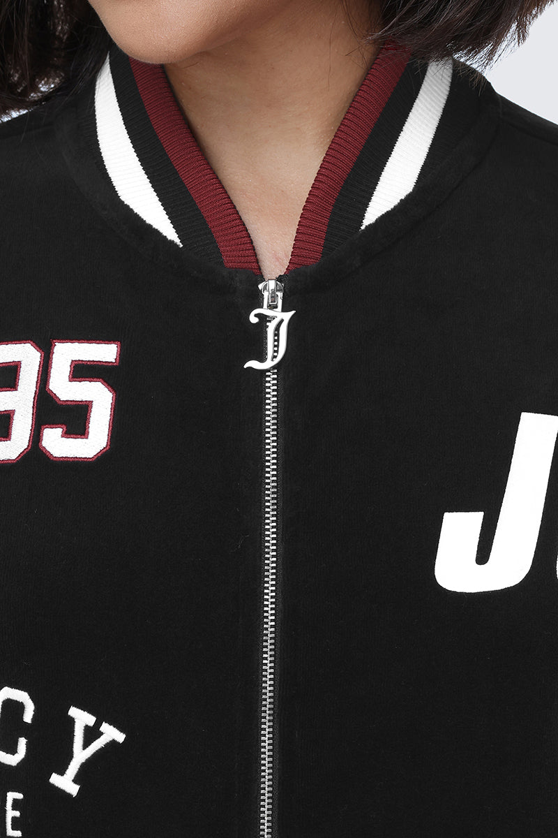 Close-up of a person wearing the Mixed Logo Cotton Velour Bomber Jacket, featuring a sporty black exterior with a striped collar, a bold white and red '95' on the left side, and a large white 'J' on the right. The jacket showcases juicy graphics throughout and has a zipper with a distinctive J-shaped pull. Only the lower face and neck are visible.