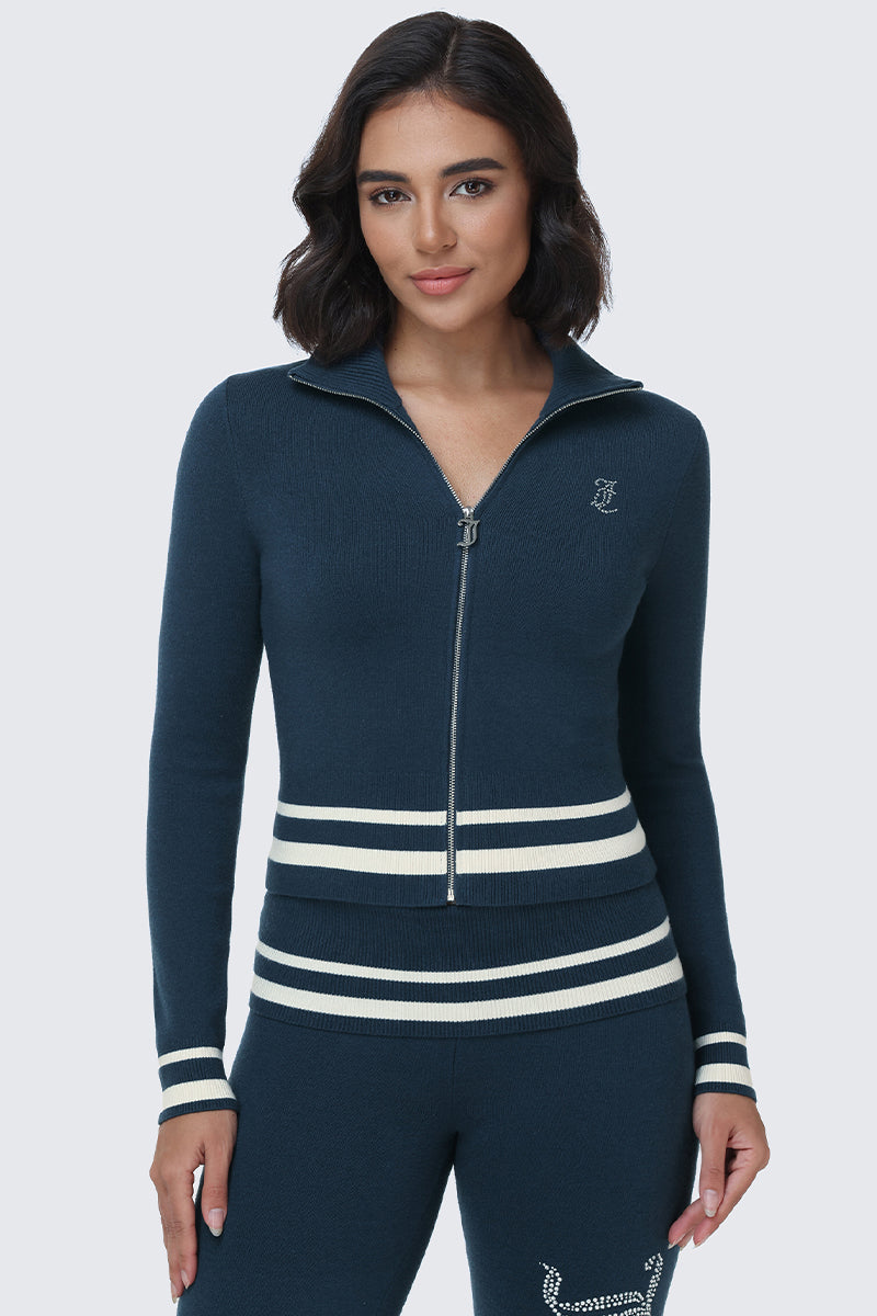 A woman wearing the Big Bling Knit Jacket in navy blue, featuring white stripes on the cuffs and waist, paired with matching navy pants and standing against a light background.