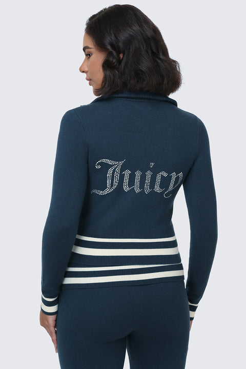 A woman wearing the Big Bling Knit Jacket—a dark blue zip-up with white striped cuffs and waist, adorned with a rhinestone Juicy logo on the back—stands against a plain light background, turned slightly to the side.
