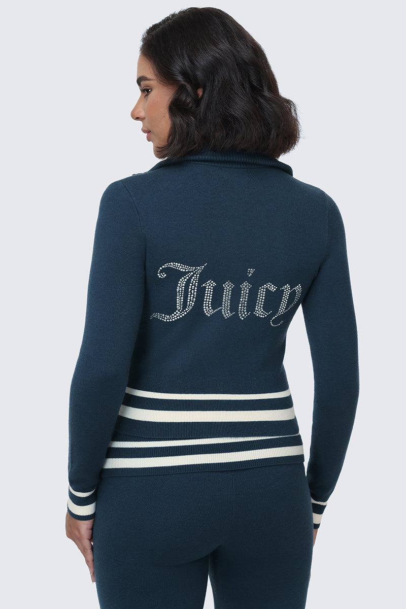 A woman wearing the Big Bling Knit Jacket—a dark blue zip-up with white striped cuffs and waist, adorned with a rhinestone Juicy logo on the back—stands against a plain light background, turned slightly to the side.