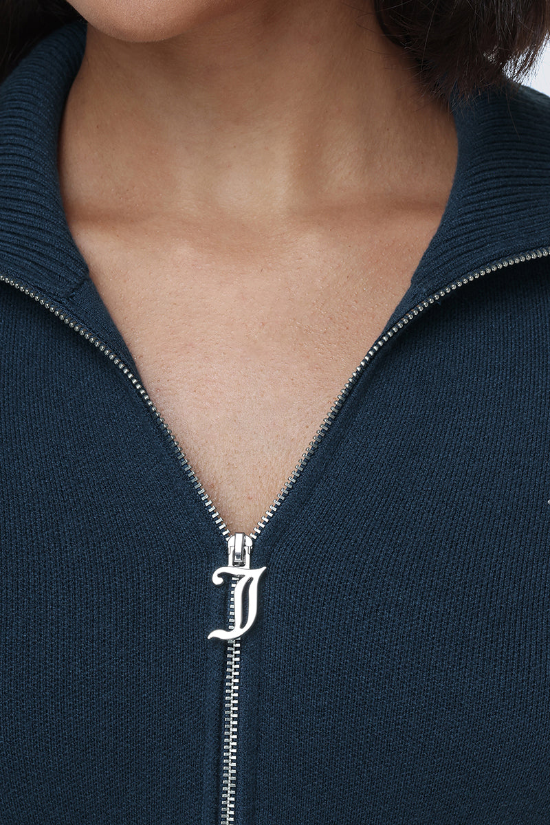 A close-up of a person wearing the Big Bling Knit Jacket in dark blue. The zipper pull is shaped like the letter J, and only the neck and upper chest are visible.