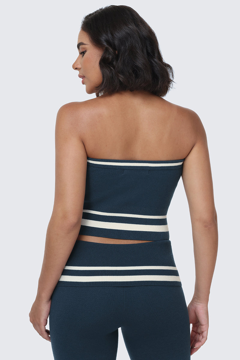 Woman with dark wavy hair wearing the Big Bling Tube Top in navy blue with white horizontal stripes, paired with matching pants, standing and facing away from the camera.