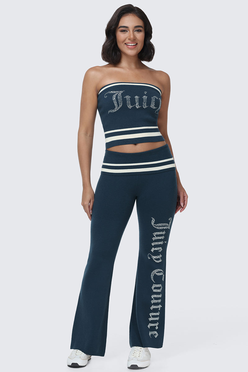 Woman wearing a navy blue Big Bling Tube Top and matching flared pants with Juicy and Juicy Couture written in rhinestones; she is smiling and wearing white sneakers.