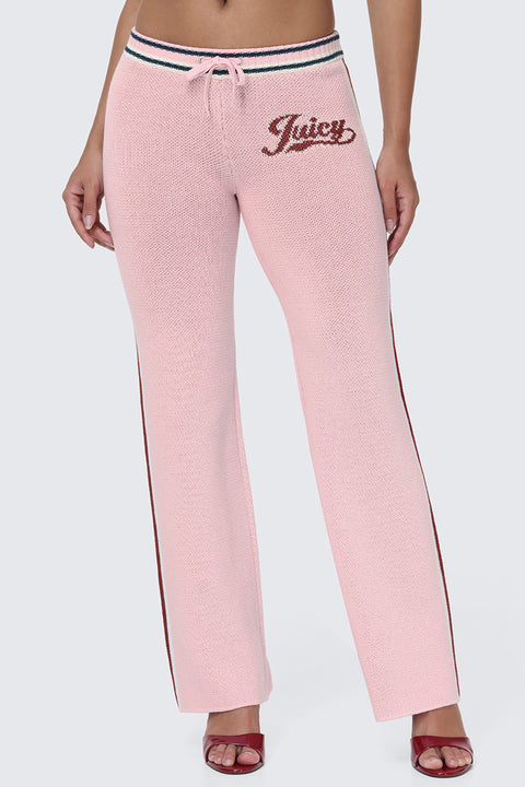 A person is wearing the Contrast Knit Wide Leg Pants, featuring a light pink knit fabric, wide legs, drawstring waist, Juicy script logo on one hip, and sporty side stripes. Paired with red open-toe heels, only the lower body is visible against a plain background, letting these standout pants take center stage.