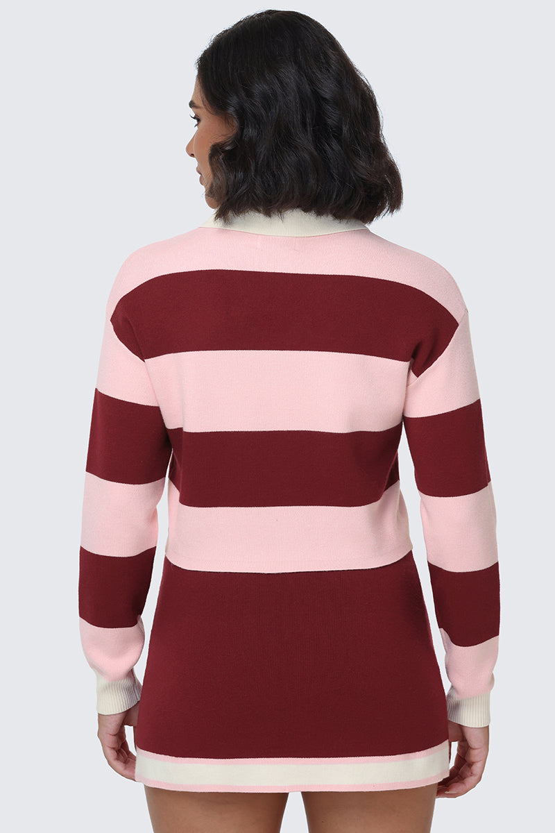 A person with shoulder-length hair is wearing the Small Bling Knit Cropped Polo, a long-sleeved, maroon and light pink striped top featuring a subtle cropped silhouette. The individual is facing away, displaying the back and arms of the garment against a plain background.