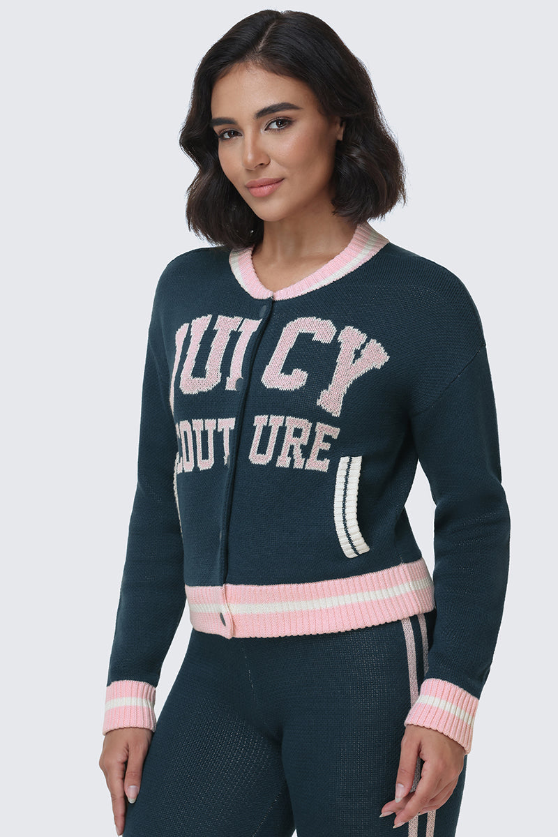 Woman with short dark hair wearing a dark green Juicy Couture Collegiate Knit Bomber Jacket featuring pink and white lettering, along with matching pants. The jacket has pink and white trim on the collar, cuffs, and pockets.